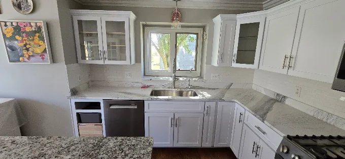 Corner sink kitchen with new white cabinet doors, quartz countertops, and glass upper cabinets