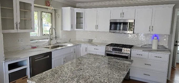 White shaker cabinets with quartz countertops and subway tile backsplash