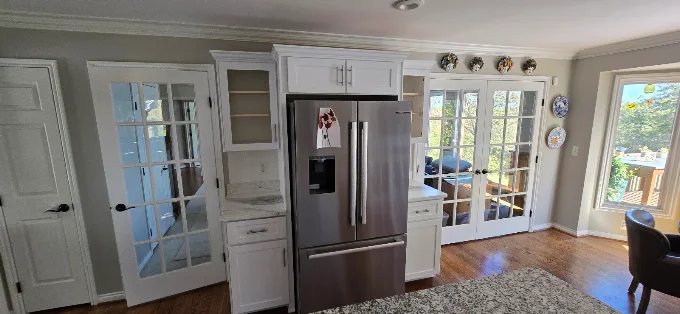 Refrigerator wall with white cabinets, glass display shelves, and French doors